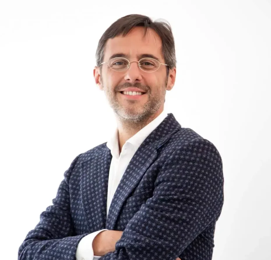 Retrato de Sergio Fernández con camisa blanca y chaqueta azul ante un fondo claro.